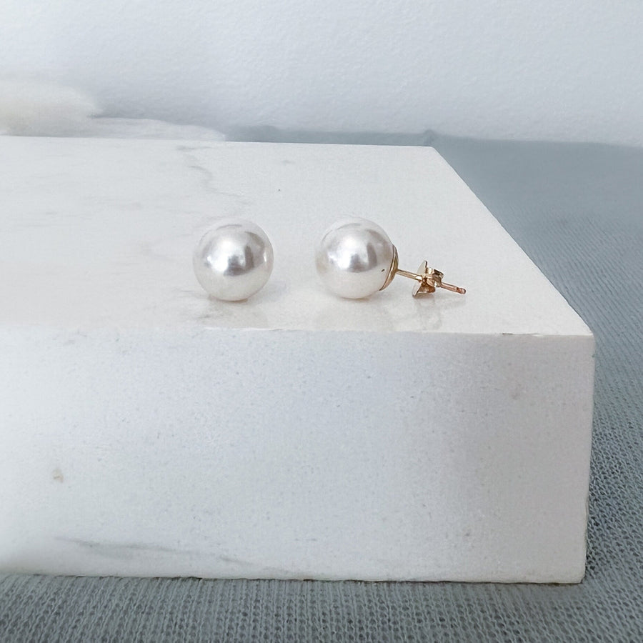 White 10mm Swarovski pearl studs in 14K gold filled settings on a white display box.