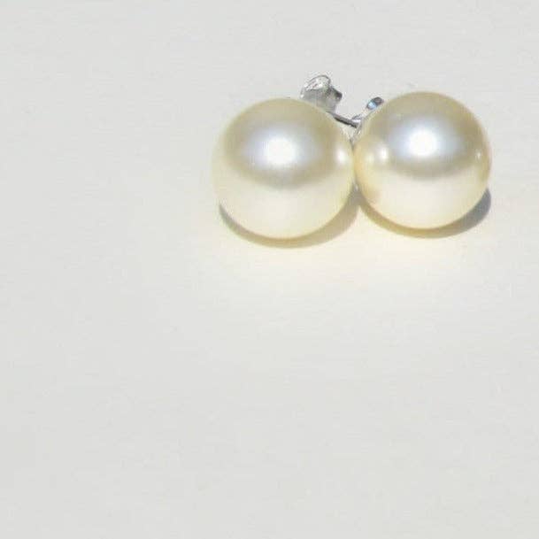 Close up of 10mm cream Swarovski crystal pearl stud earrings with a warm, buttery luster.