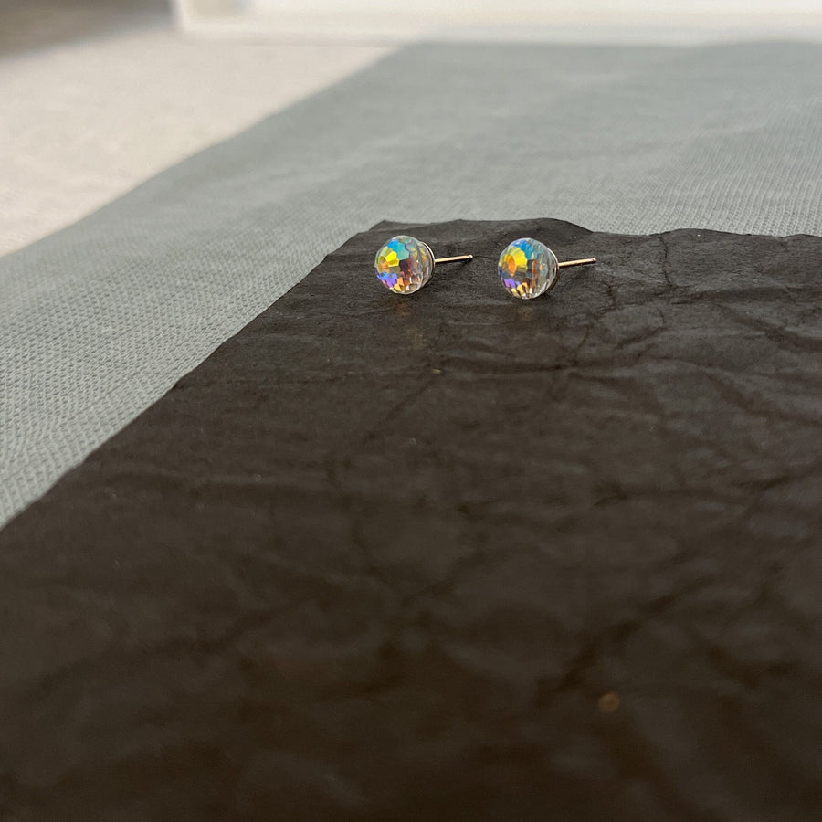 one pair of Swarovski AB crystal ball earrings, in a gold setting on a black background.