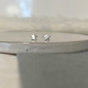 Silver star-shaped earrings on a neutral background
