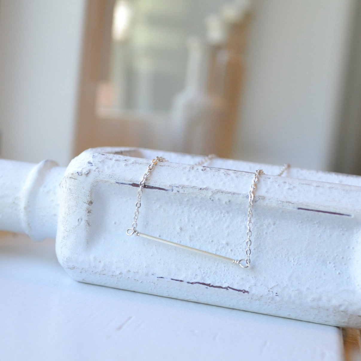 Sleek sterling silver bar necklace with a thin flat horizontal pendant, minimalist jewelry handcrafted by Sela and Sage.