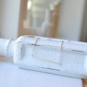 Sleek sterling silver bar necklace with a thin flat horizontal pendant, minimalist jewelry handcrafted by Sela and Sage.