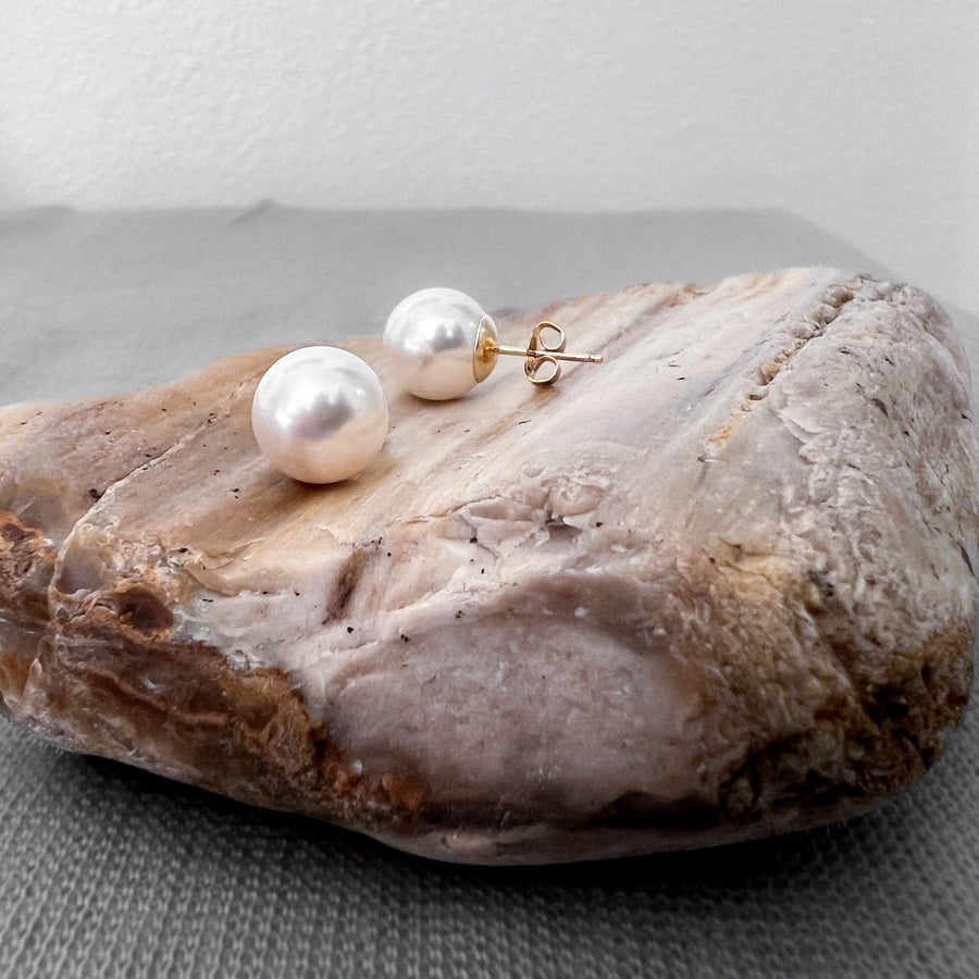 Close up of 10mm white Swarovski crystal pearl stud earrings with brilliant luster.